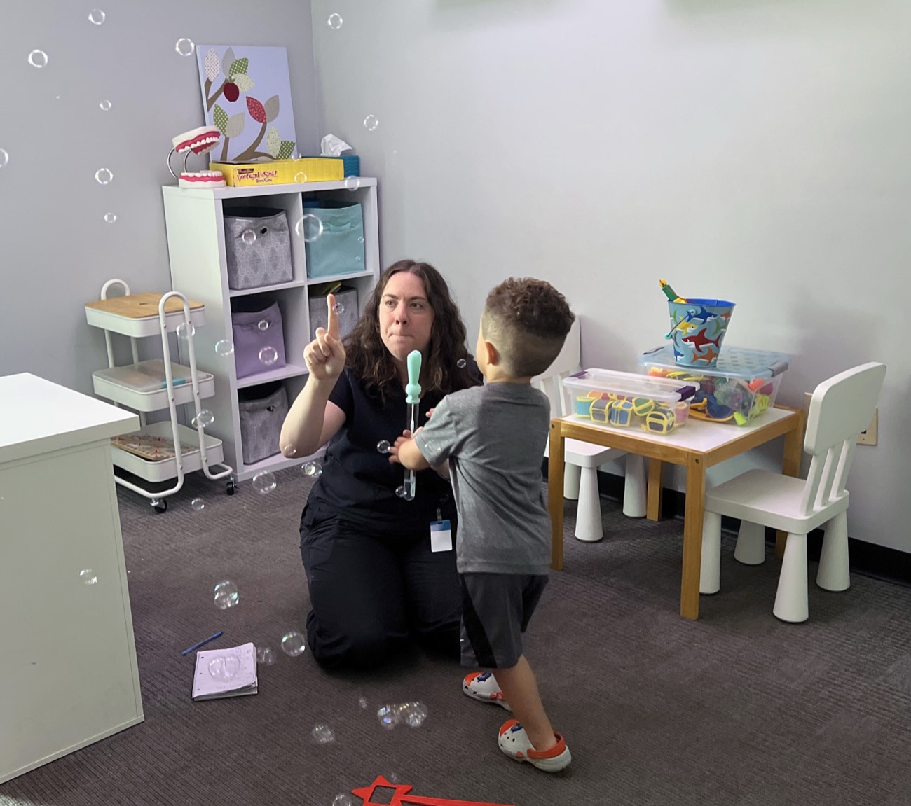 An UpWords speech therapist blowing bubbles with a young child in the therapy room